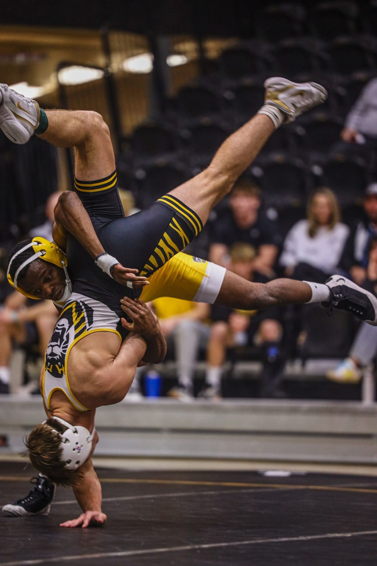 A wrestler flipped upside down in mid-throw during a dual
