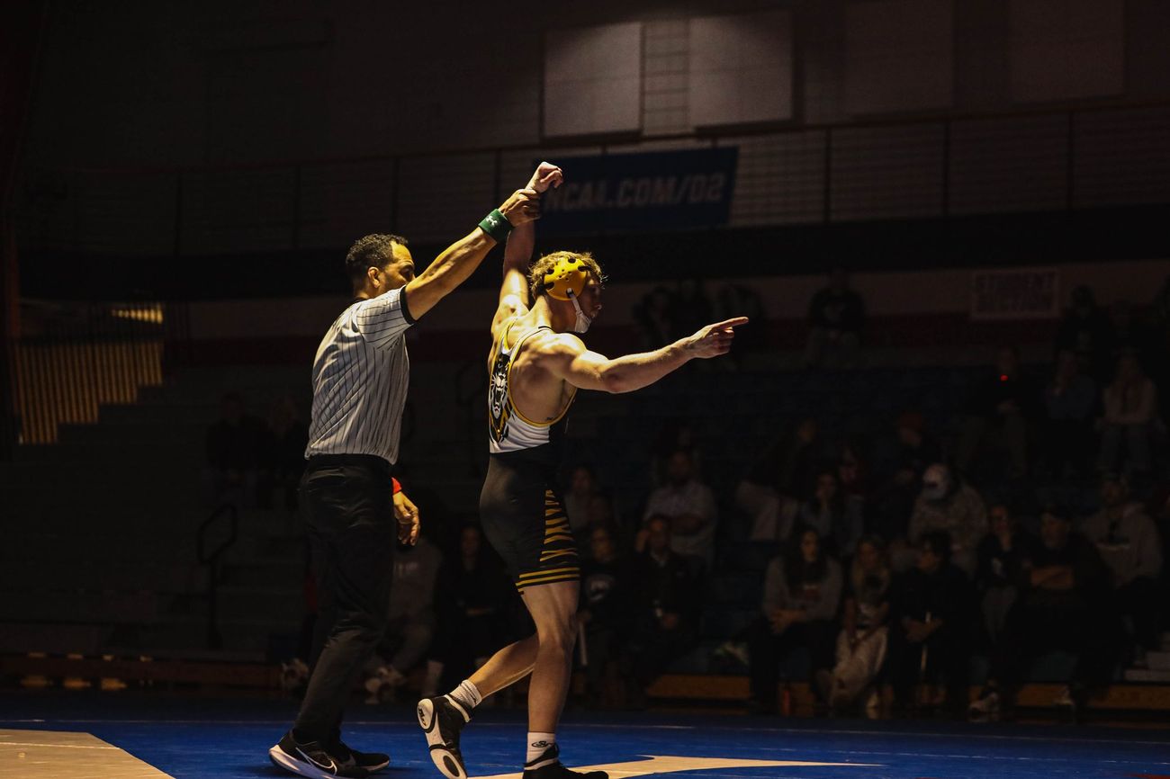A referee raising a wrestler's arm after a dual against Newman