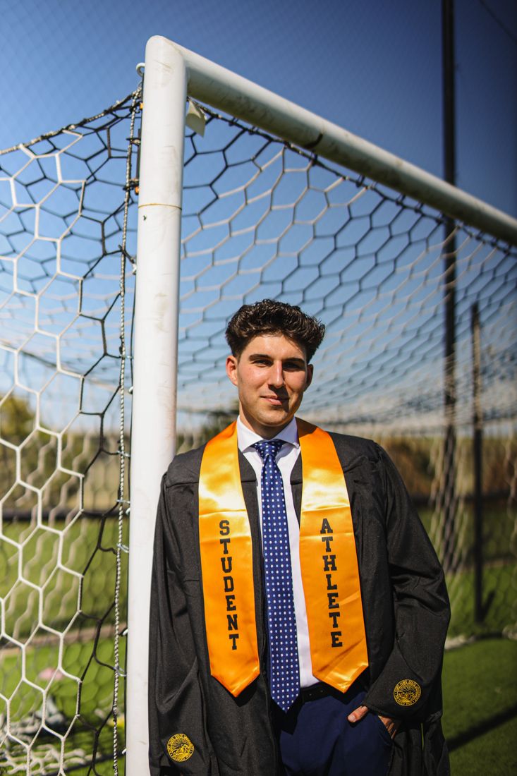 A graduate with a Student Athlete stole standing in front of a soccer goal